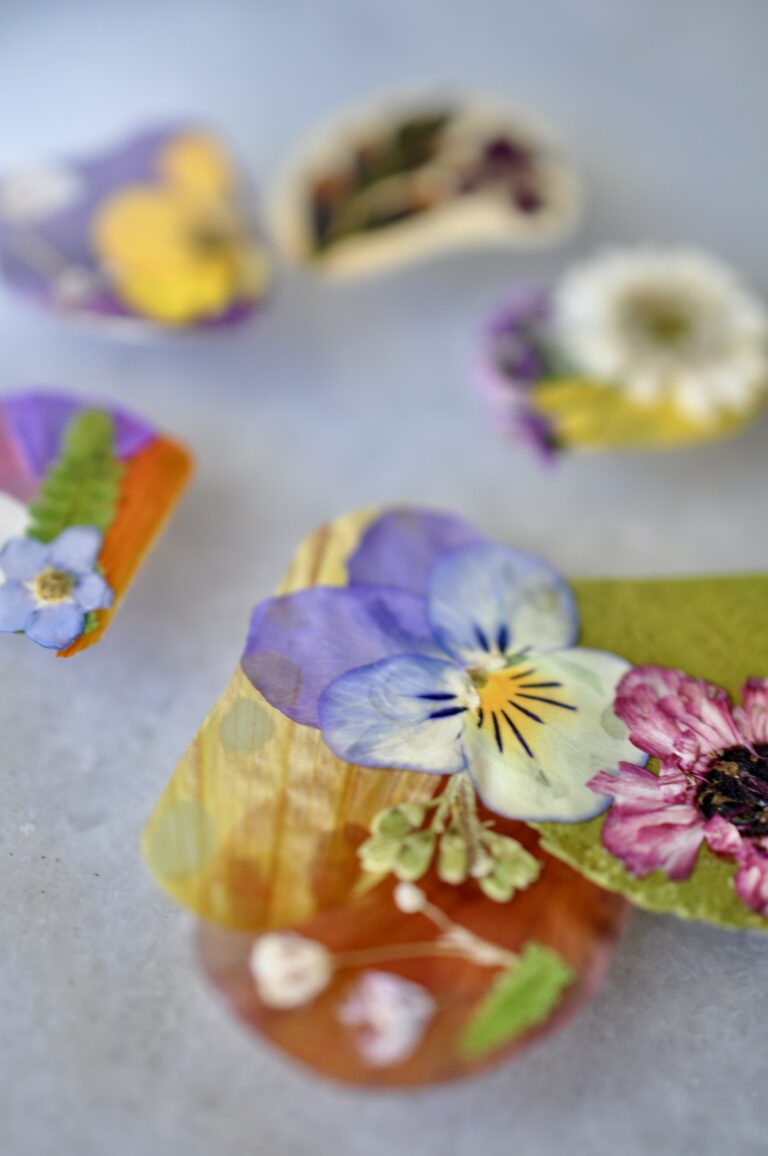 Close-up view of a handmade dog paw print made from real pressed flowers in vibrant colors.