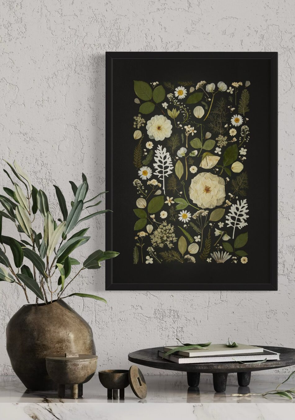 Framed fine art print of white and green pressed flowers arranged against a black background, styled on a textured wall with rustic décor