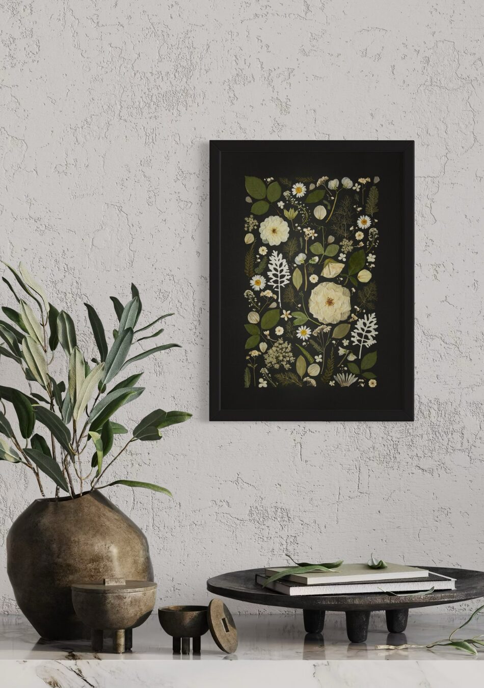 Framed fine art print of white and green pressed flowers arranged against a black background, styled on a textured wall with rustic décor