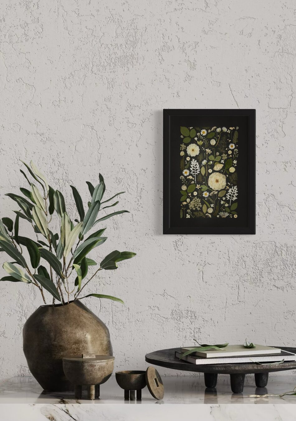 Framed fine art print of white and green pressed flowers arranged against a black background, styled on a textured wall with rustic décor