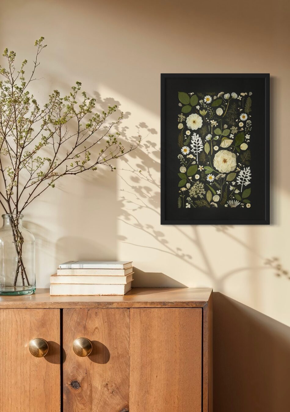 Framed fine art print of white and green pressed flowers arranged against a black background, styled on a textured wall with rustic décor