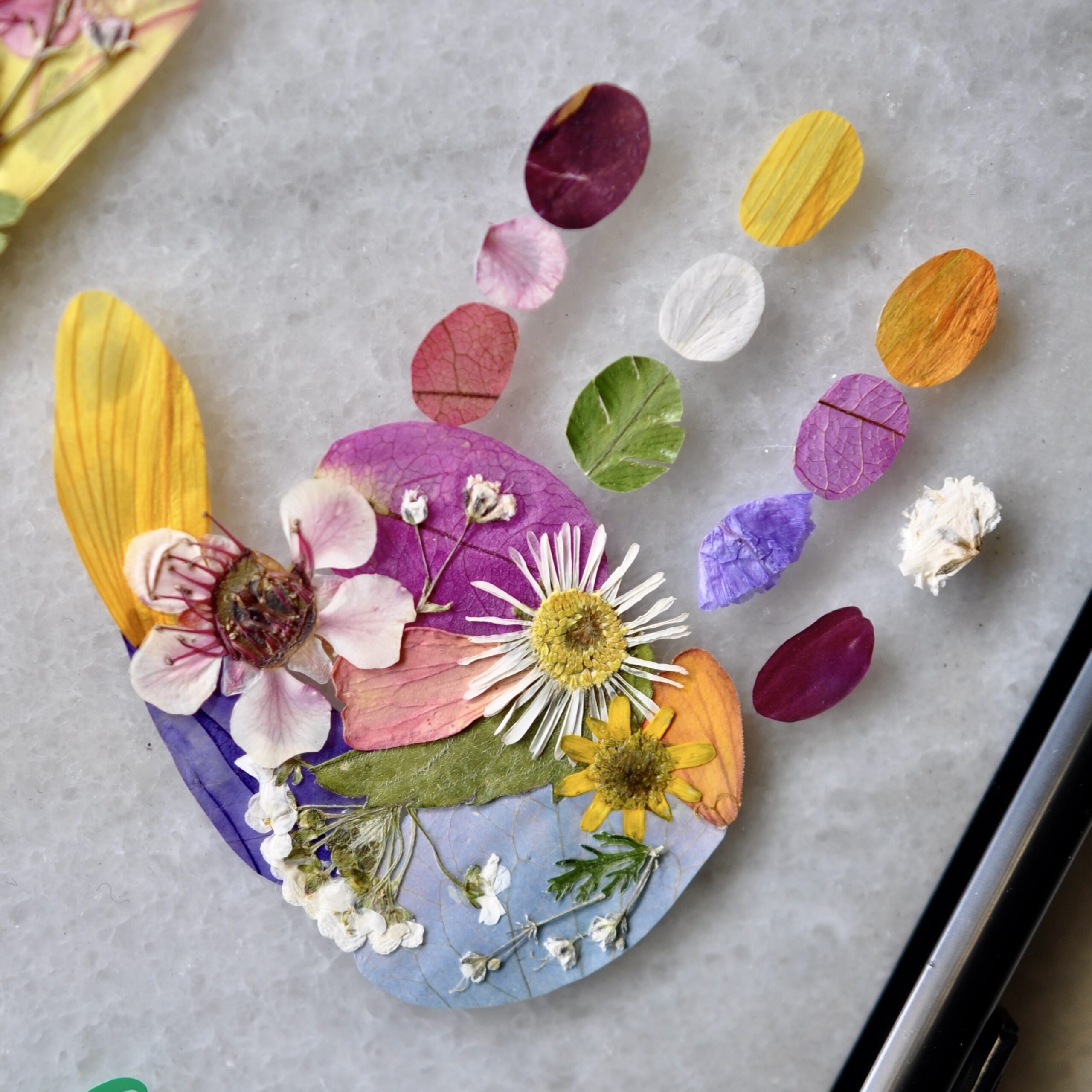 Close-up of handprint out of pressed flowers as a unique baby keepsake