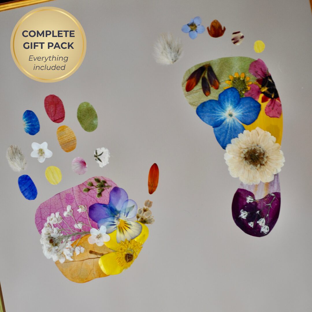 Luxury framed baby footprint artwork made with pressed flowers and personalised gold lettering, presented as a complete gift pack with voucher and print kit.