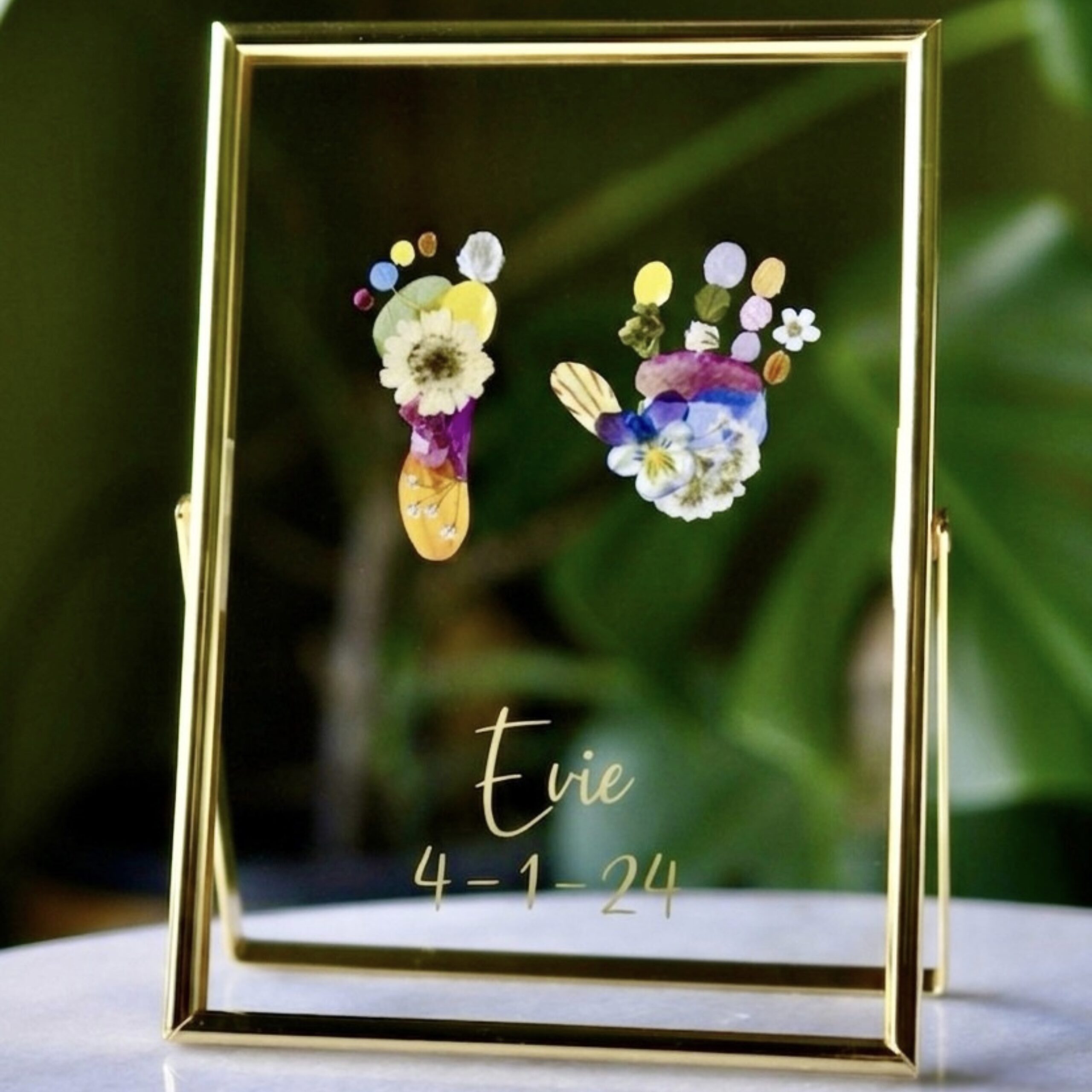 Tiny hand and footprint out of pressed flowers in golden floating Fram