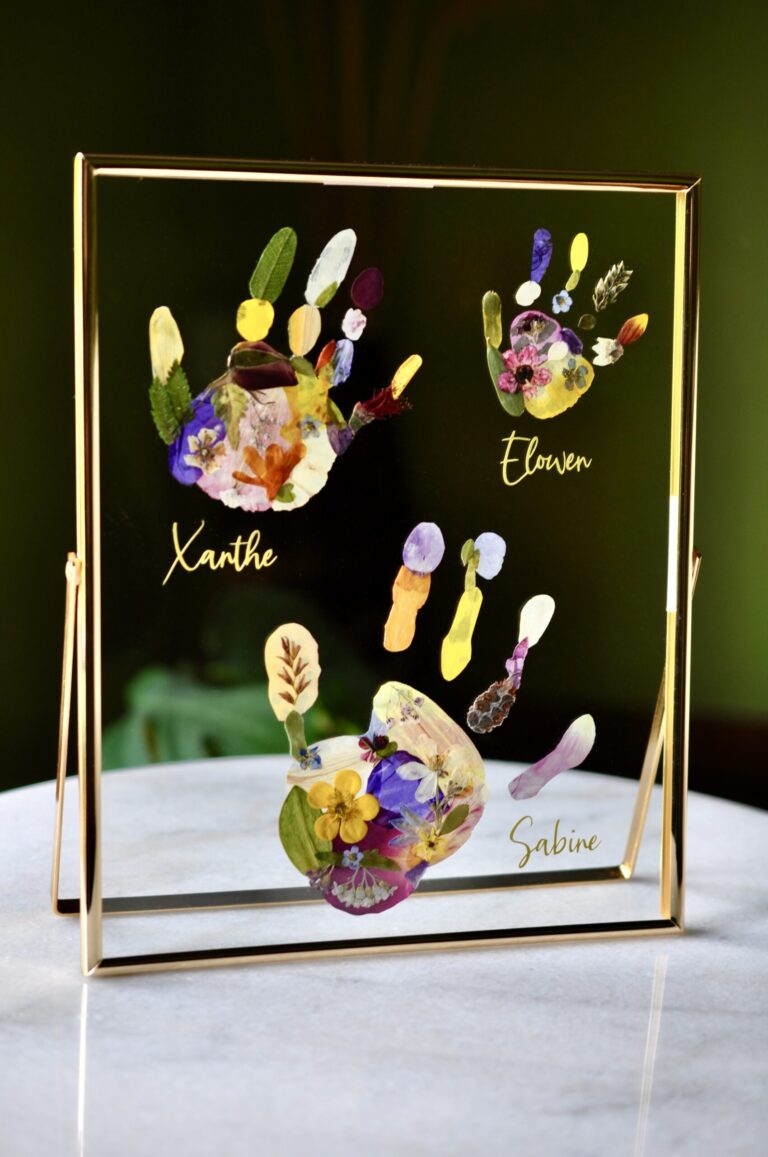 3 handprints put of pressed flowers in a glass floating frame with names